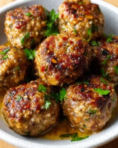 Keto garlic butter meatballs served on a plate with fresh herbs